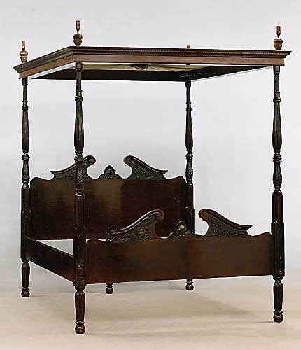 English mahogany four-poster bed with full tester: tester with dentil-molded cornice installed with gathered fabric and having poles and rings for drapery panels, on turned, carved and reeded posts flanking headboard with broken swan's-neck pediment c