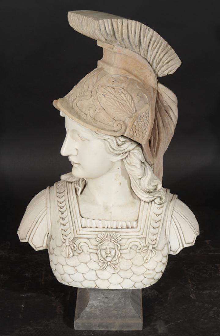CARVED MARBLE TRAVERTINE ROMAN INSPIRED BUST: A carved marble and travertine Roman inspired bust with ornate helmet and scaled breast plate all raised on stepped base. Ht: 37" Wd: 22" Dpth: 12"