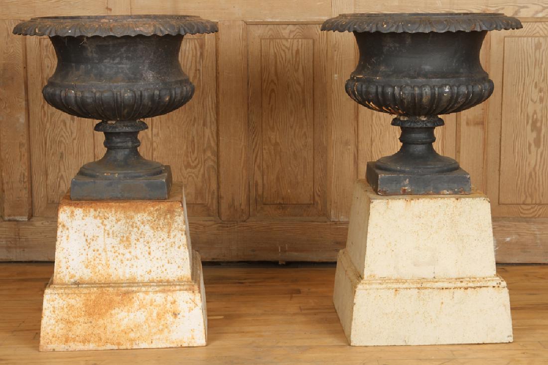 PAIR CLASSIC CAST IRON GARDEN URNS CIRCA 1910: A pair of classic cast iron garden urns having egg and dart rim, fluted bowls and stepped bases circa 1910. Urn only: 17" x 19.5" Ht: 34" Dia: 19" (overall)