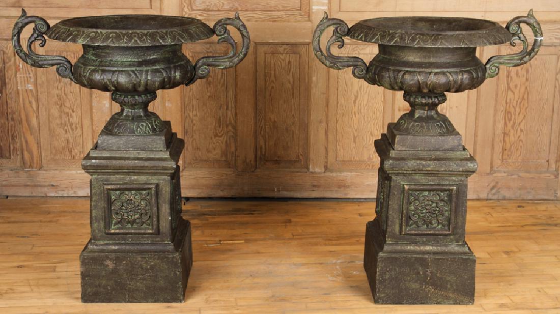 CAST IRON GARDEN URN ON DECORATED IRON BASE: A one piece cast iron garden urn with handles resting on a separate decorated iron base. Ht: 38" Wd: 31" Dpth: 22" (overall)