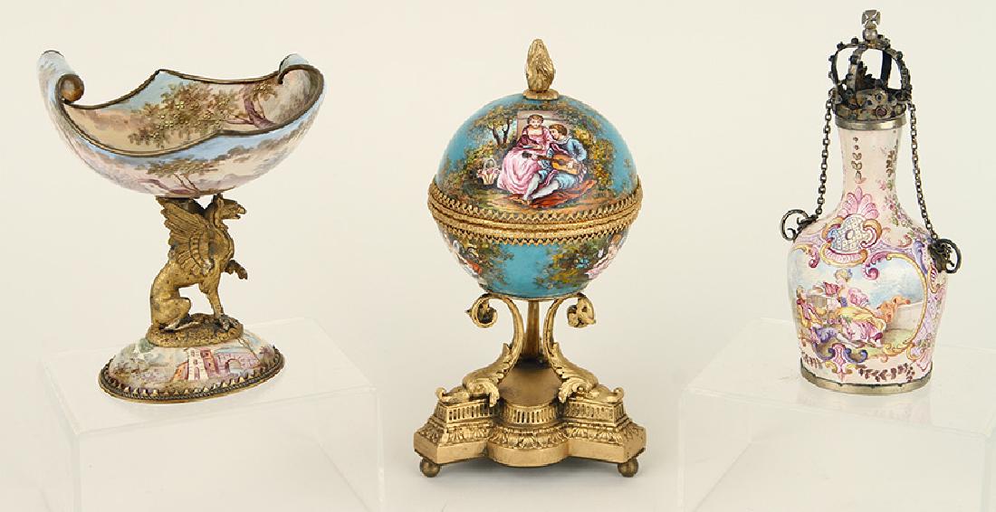 COLLECTION OF THREE VIENNESE ENAMELED ITEMS: A collection of three Viennese enameled items. Comprised of: A music box raised on dolphin supports having velvet lined interior: 6.25" A salt raised on griffin support: 4.25" A small decanter with cr