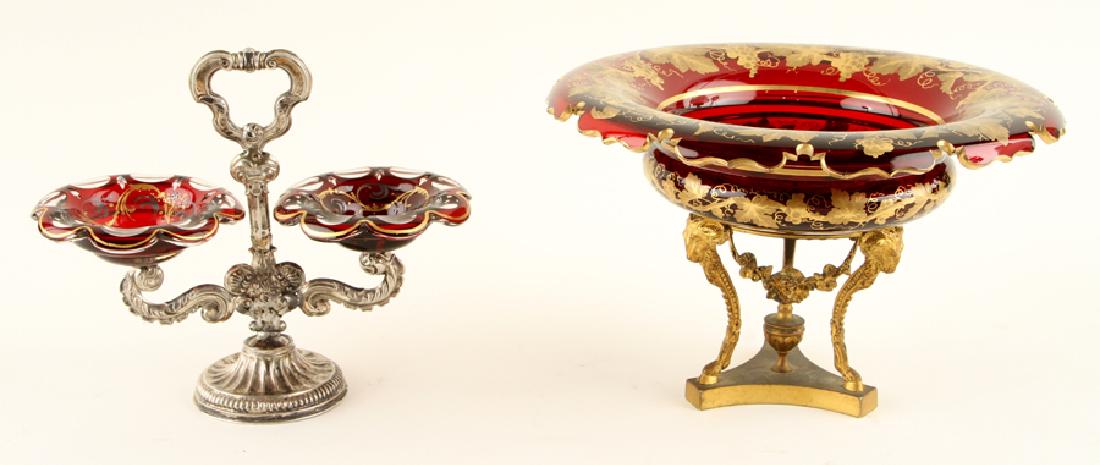 TWO 19TH C. CONTINENTAL RUBY GLASS COMPOTES: A group of two nineteenth century Continental ruby Bohemian glass compotes raised on gilt bronze and silver stands. The larger compote having gilt enameled leaf design to rim of removable bowl and rai