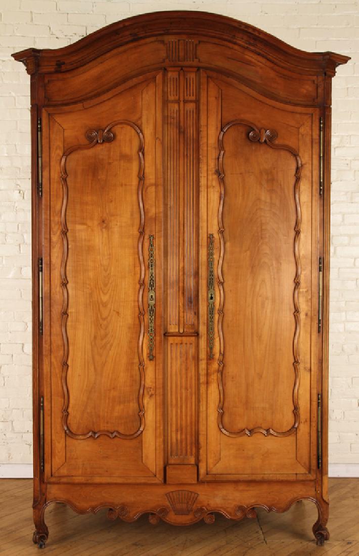 19TH C. FRENCH CHERRY ARMOIRE ARCHED TOP: An elegant nineteenth century French cherry armoire having an arched top over two shaped doors with brass escutcheons. Ht: 102" Wd: 65" Dpth: 26"