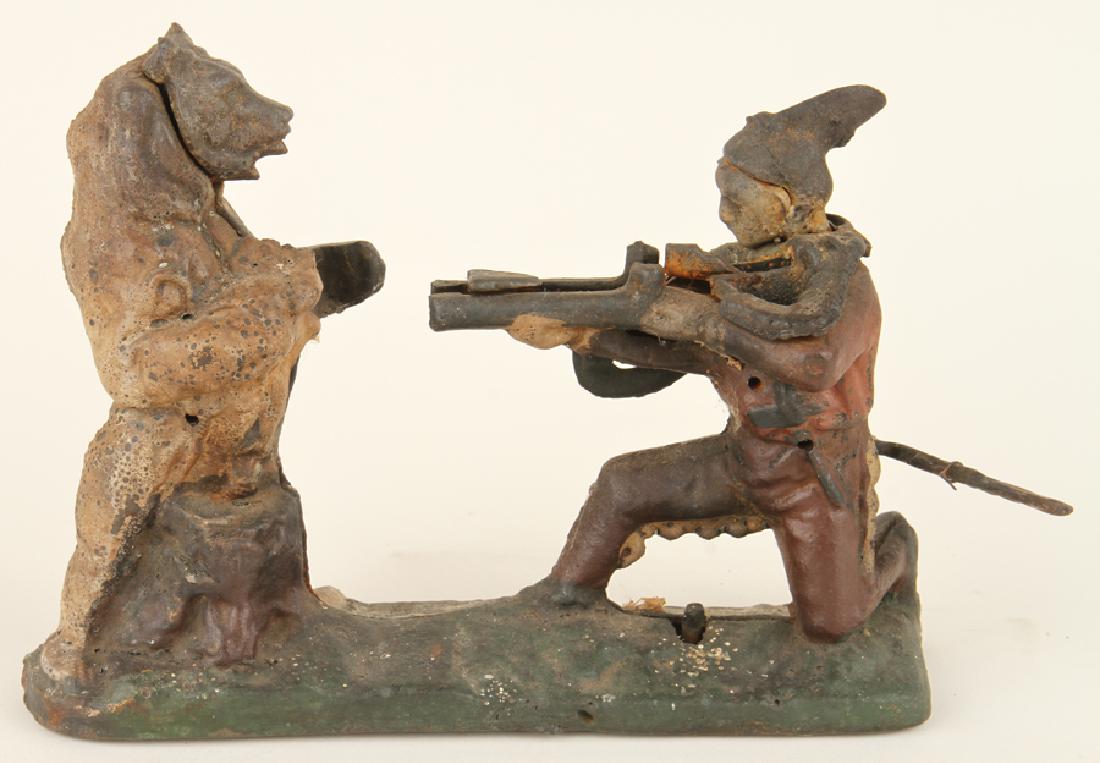 CAST IRON NATIVE AMERICAN BEAR HUNTER COIN BANK: An antique cast iron Native American bear hunter coin bank. Having a kneeling figure and standing bear. Ht: 9.25" Wd: 10" Dpth: 3"