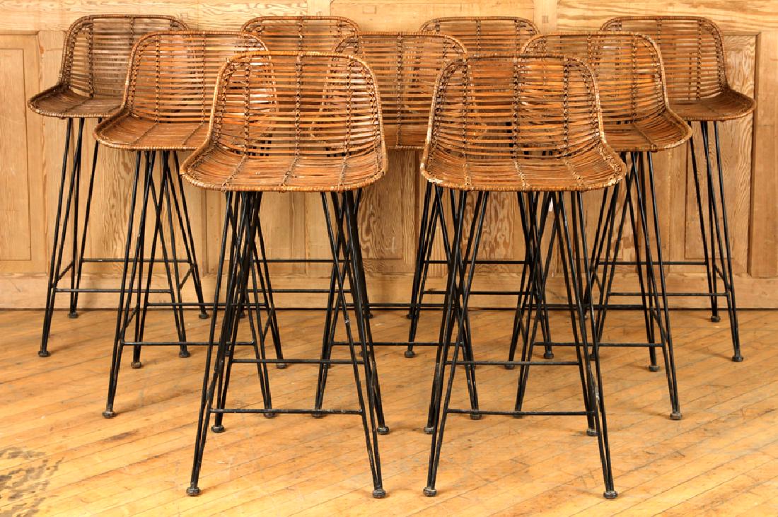 SET OF NINE RATTAN BAR STOOLS ON IRON LEGS C.1970: A set of nine rattan bar stools resting on iron legs circa 1970. Ht: 34.75" Wd: 16.5" Dpth: 18.5" Seat: 26"