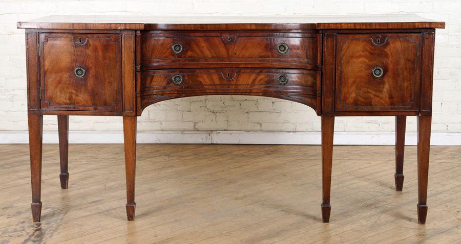 GEORGE III MAHOGANY SIDEBOARD C. 1800: A George III mahogany sideboard circa 1800 having two concave drawers flanked by a door and a wine drawer. Ht: 35.5" Wd: 72" Dpth: 25.5"