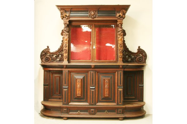 LARGE ANTIQUE FIGURAL CARVED BUFFET: Large antique figural carved buffet with stepped cornice with lion carved corners circa 1890. Over glass front cabinet decorated with herald and crest carved figures over base with ebonized raised pan