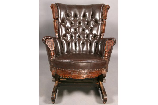 ANTIQUE VICTORIAN CARVED WALNUT ROCKING CHAIR: Interesting American Victorian carved walnut rocker with tufted back raised on a reclining platform circa 1890. Having arms decorated with stylized floral and geometric columns. Ht: 36" Width: 32" Dep