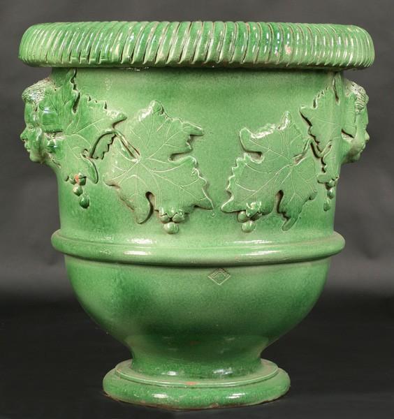 LARGE GREEN GLAZED EARTHENWARE GARDEN PLANTER: A large scale green glazed earthenware garden planter in the French taste with reeded roll rim over applied faces. Ht: 31" Diameter: 29"