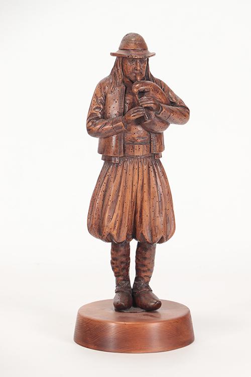 CARVED WOOD STATUE MAN PLAYING MUSICAL INSTRUMENT: A carved wood statue depicting man playing a musical instrument. Ht: 20.5" Wd: 8"