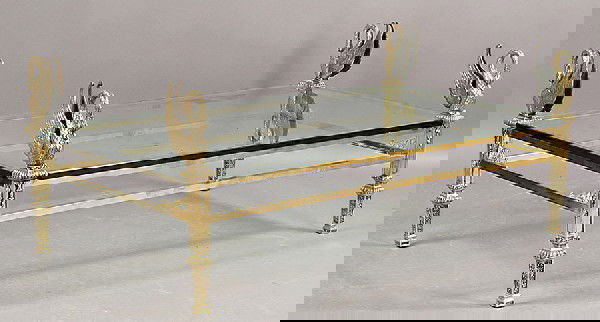 ORNATE BRASS BRONZE COFFEE TABLE GLASS TOP: Ornate brass and bronze coffee table with swan ornamented corners over glass top supported on rectangular frames with tapered legs circa 1950. Ht: 22" Width: 56" Depth: 31"