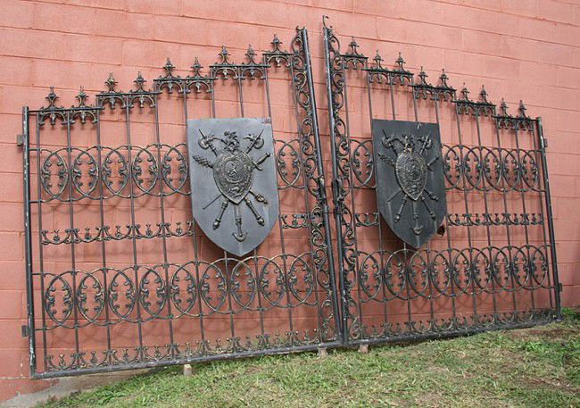 MONUMENTAL PAINTED CAST IRON ENTRY GATES: Monumental painted cast iron mansion entry gates having heraldic plaques. Ht: 101" Width: 168" Depth: 7" Terms & Conditions: PLEASE NOTE: All property shall be paid for by the purchaser within five (5