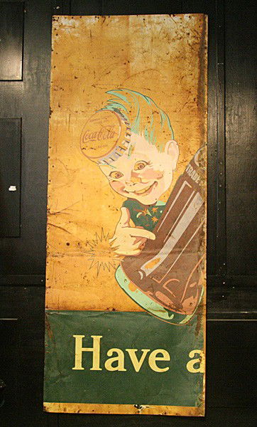 VINTAGE COCA COLA PAINTED TIN ROADSIDE SIGNAGE: Vintage Coca-Cola painted tin roadside signage, showing a pixie in a Coke cap hat pointing at a vintage style glass bottle circa 1940. This large broadside advertisement was found on the side of a bar