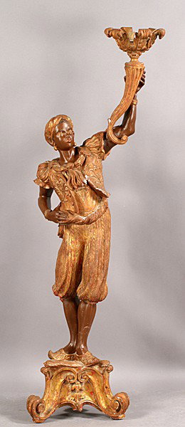 PAINTED PLASTER BLACKAMOOR ON STAND: A painted plaster blackamoor on stand having an outstretched arm holding a torch. Ht: 74" Width: 21" Depth: 19"