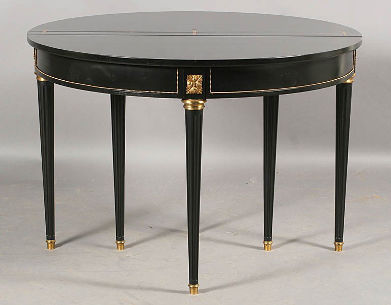LOUIS XVI BRONZE MOUNTED FLIP TOP DINING TABLE: A French Louis XVI style bronze mounted console form dining table having three beaded and foliate decorated aprons circa 1940. Having two leaves each measuring 12". Ht: 30" Diameter: 43"