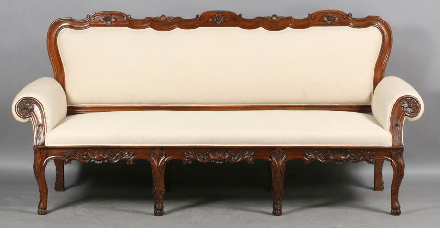 ANTIQUE FRENCH CARVED WALNUT SETTEE UPHOLSTERED: A good antique French carved walnut settee having triple crest rail over upholstered back and seat circa 1870. Having a carved apron supported on acanthus decorated cabriole leg with stylized hoof fee