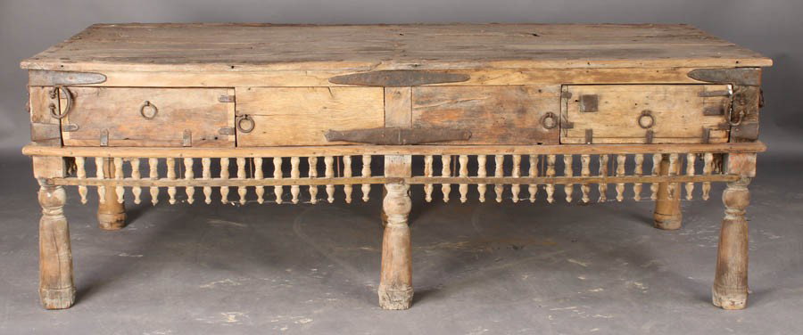 LARGE ANGLO INDIAN WORK TABLE PLANK TOP METAL: A large Anglo Indian work table having a plank top with metal riveted trim. Over an apron with large wrought iron handles, and decorated border raised on turned legs. Dimensions: Ht: 27" Width: 77.5" 