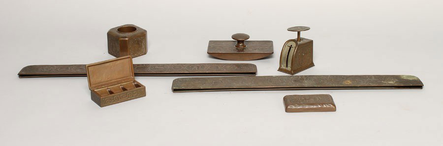 8 PC TIFFANY STUDIOS BRONZE DESK SET ZODIAC: An eight piece Tiffany Studios bronze desk set in the Zodiac pattern circa 1900. Consisting of desk blotter, edges, paper weight, stamp box, postage scale, ink well, picture frame, and blotter. Ht: 7"