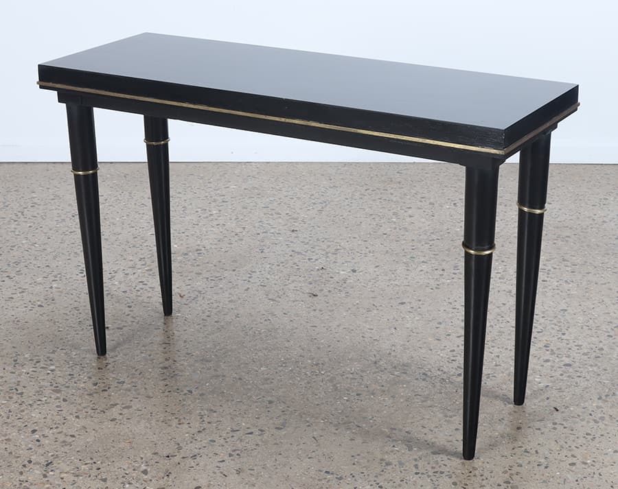 A SLEEK EBONIZED CONSOLE TABLE WITH BRASS TRIM CIRCA 1950 IN THE MANNER OF ANDRE ARBUS: A sleek ebonized console table with brass trim circa 1950 in the manner of Andre Arbus. Ht: 30.75" Wd: 47.5" Dpth: 17.25"