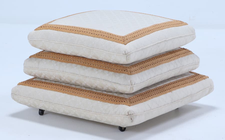 A STACKED PILLOW OTTOMAN HAVING EMBROIDERED BORDER RAISED ON CASTERS. (1 of 5)