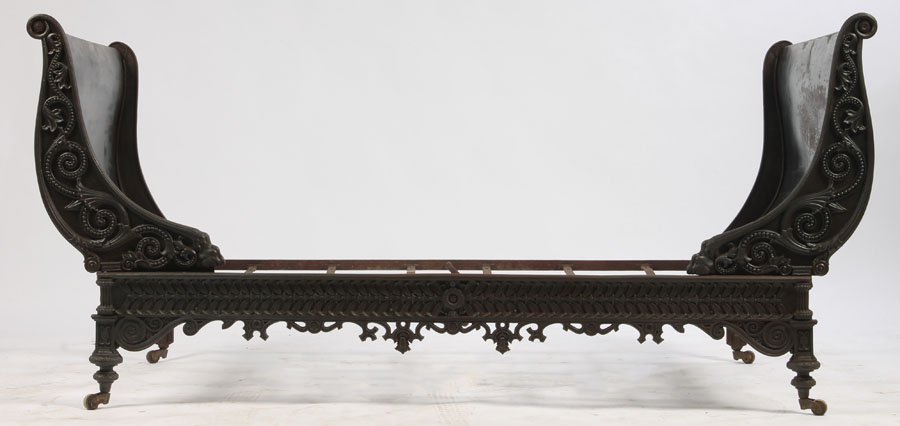 IRON FRENCH EMPIRE STYLE SLEIGH DAYBED: A very good French cast iron Empire style daybed having sleigh bed ends and ornate front apron circa 1870. The whole raised on casters. Ht: 38" Width: 67.5" Depth: 45"