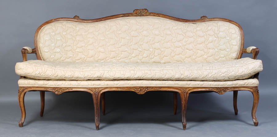 ANTIQUE FRENCH CARVED WALNUT SETTEE SERPENTINE: Antique French Louis XV style carved walnut settee having a serpentine crest rail with central floral carving over open arms circa 1800. With loose cushion seat and eight shaped legs. Ht: 33" Width: 7