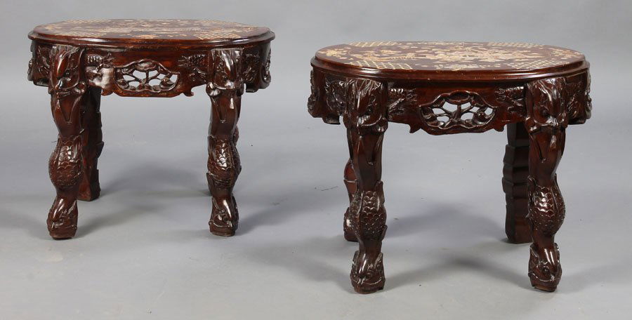 PAIR HEAVILY CARVED INLAID ASIAN SIDE TABLES: A pair of elaborately carved and inlaid Asian side tables having mother-of-pearl decorated tops over pierce carved apron and fish carved legs. With mother-of-pearl inlaid story scenes and floral bouqu