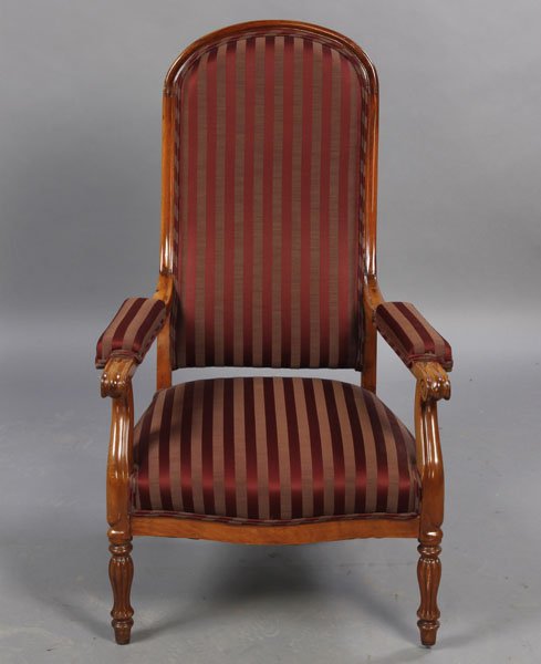 EDWARDIAN STYLE LIBRARY CHAIR UPHOLSTERED: An Edwardian style library chair having a high upholstered back over open arms with scrolling decoration and fitted seat circa 1900. Raised on turned and reeded legs. Ht: 43.5" Width: 26.5" Depth: 21"