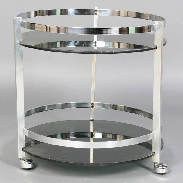 MID CENTURY MODERN SERVING CART CHROME GLASS: A mid century modern two-tiered chrome and black glass serving cart circa 1970. Now lacking top glass. Ht: 23.5" Dia: 22"