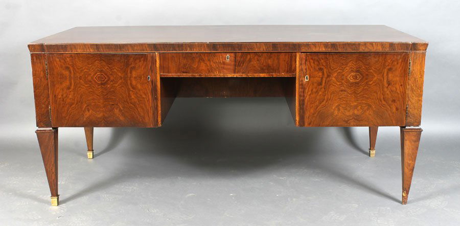 ANDRE ARBUS STYLE WALNUT DESK C.1950: Stylish Andre Arbus style desk having a figured walnut top over a single drawer and two doors on tapered legs with bronze sabots circa 1950. Ht: 32" Width: 73.5" Depth: 35.5"