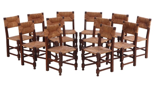TWELVE FRENCH OAK DINING CHAIRS HAVING RUSH SEATS AND BACKS IN THE MANNER OF CHARLES DUDOUYT C 1940.