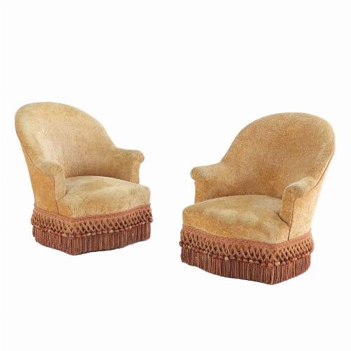A pair of French Napoleon III lounge chairs C 1860 .: The oval-back frames, and scroll arms are resting on ebonized turned legs. This great pair of cozy chairs has been recovered at some point with a soft luxurious fabric and fun fringe.This item is not 