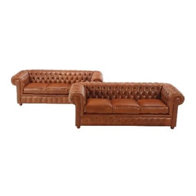 A pair of leather Chesterfield style sofas .