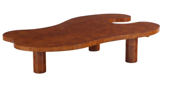 A SHAPED BURL WOOD COFFEE TABLE RESTING ON THREE ROUND LEGS.