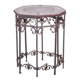 A MORGAN COLT (ATTR.) IRON GARDEN TABLE HAVING A SEGMENTED STONE TOP RESTING ON ELABORATELY