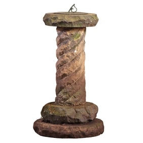 BRONZE SUNDIAL RESTING ATOP A CARVED STONE PEDESTAL.