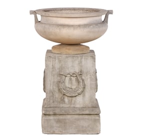 A ROMAN STYLE POT WITH HANDLES BY HADDONSTONE SITTING ATOP A CAST STONE PEDESTAL.