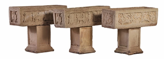 THREE MATCHING DECORATED CAST STONE PLANTERS RESTING ON SEPARATE PLINTHS.
