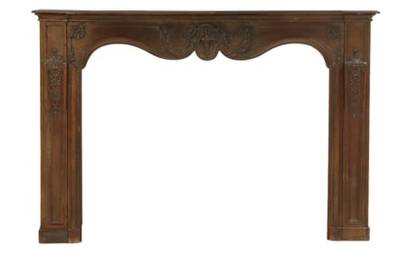 A CARVED OAK 18TH CENTURY FRENCH FIREPLACE MANTLE HAVING SHAPED APRON AND FOLIATE AND FLORAL