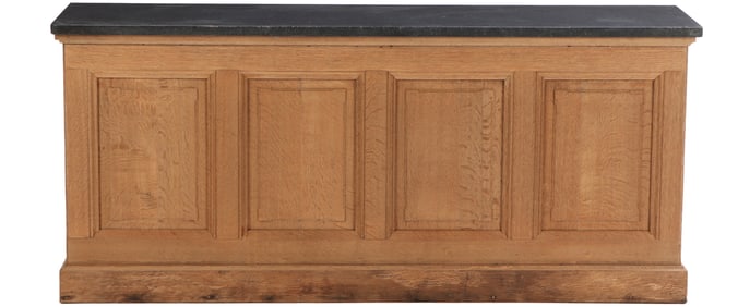 A LARGE OAK ANTIQUE FRENCH COUNTER HAVING RECESSED PANELS AND BLUE STONE TOP C 1900.