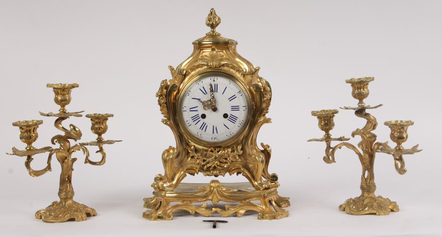 ROCOCO MANTLE CLOCK & PAIR OF CANDELABRUM C.1920: Elaborate gilt bronze Rococo style mantle clock with fine enamel dial pendulum and key and a complimentary pair of candelabrum circa 1920. Ht: 11.5" Width: 11" Depth: 7"