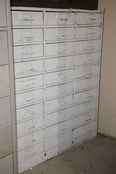 A MULTIPLE DRAWER CASE OF LAMP PARTS: A multiple drawer case of lamp parts including finials, harps, and rods. Ht: Width: Depth: