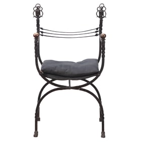 AN ANTIQUE WROUGHT IRON CURULE CHAIR IN THE MANNER OF OSCAR BACH HAVING BIRD FORM FINIALS CIRCA