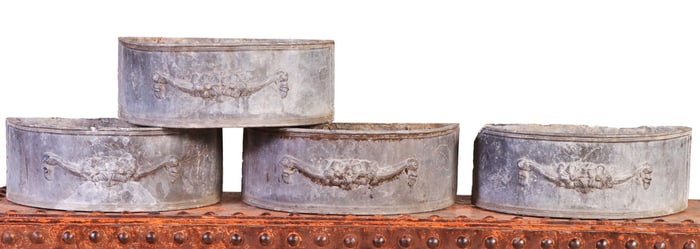FOUR LEAD DEMILUNE PLANTERS WITH SWAG DECORATION.