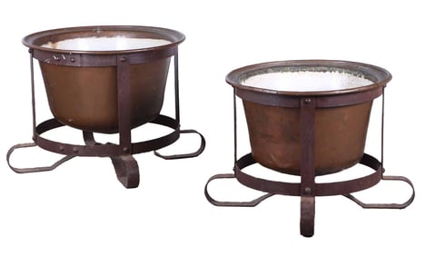 A PAIR OF LARGE COPPER PLANTERS RAISED ON ELABORATE IRON STANDS.