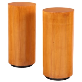 A PAIR OF CYLINDRICAL MAPLE PEDESTALS HAVING RECESSED EBONIZED BASES.