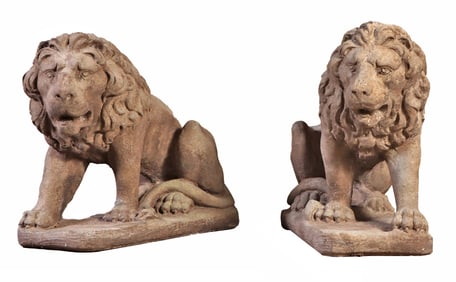 A PAIR OF CAST STONE LIONS CROUCHING ON A RECTANGULAR BASE.