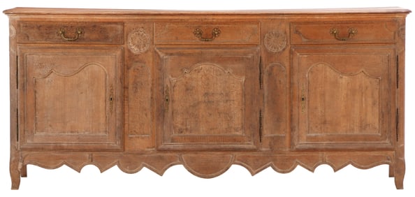 LARGE NINETEENTH CENTURY FRENCH OAK BUFFET HAVING A SHAPED SKIRT AND CARVED PINWHEELS.