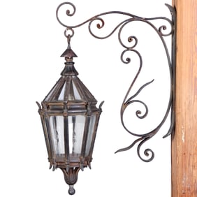 CAST IRON AND GLASS LANTERN HANGING FROM AN IRON BRACKET C 1920.