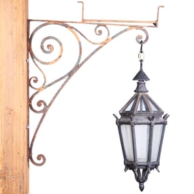 CAST IRON LAND GLASS LANTERN HANGING FROM AN IRON BRACKET C 1920. BRACKET IS INVERTED IN PHOTO AND